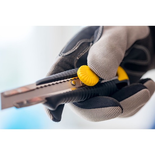 STANLEY 0-10-418 utility knife with yellow dial, held in gloved hand, close-up photography.