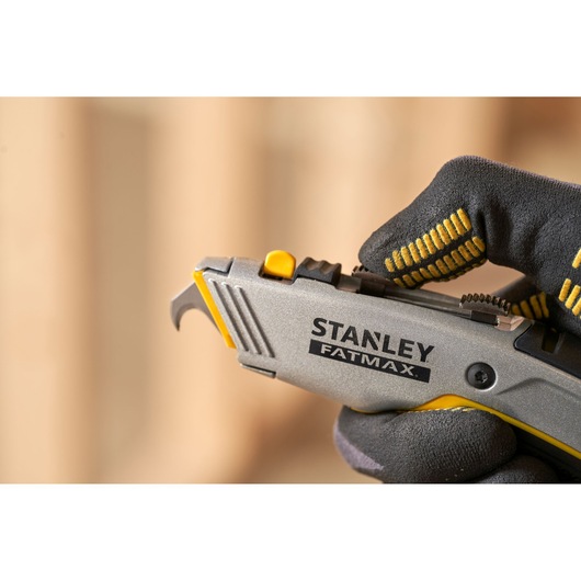 STANLEY 0-10-789 utility knife close-up, held in gloved hand, FATMAX branding visible.
