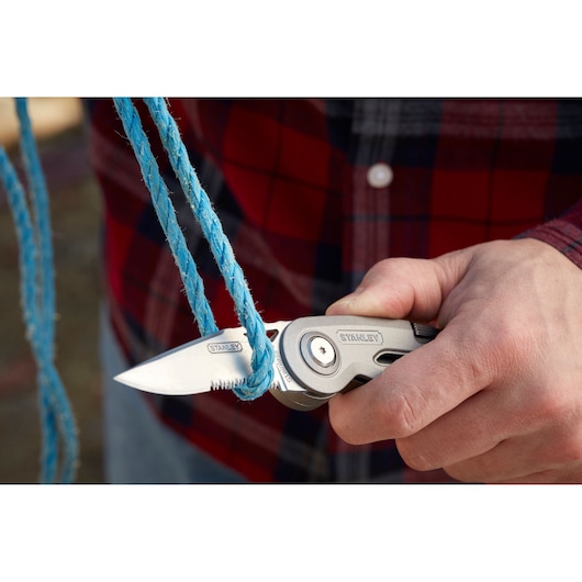 STANLEY 0-10-813 folding utility knife cutting blue rope, close-up view.