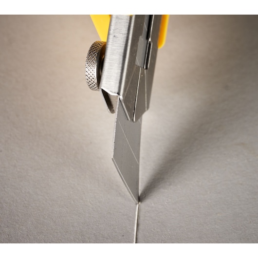 STANLEY 0-11-718 utility knife blade cutting grey material, close-up photography.