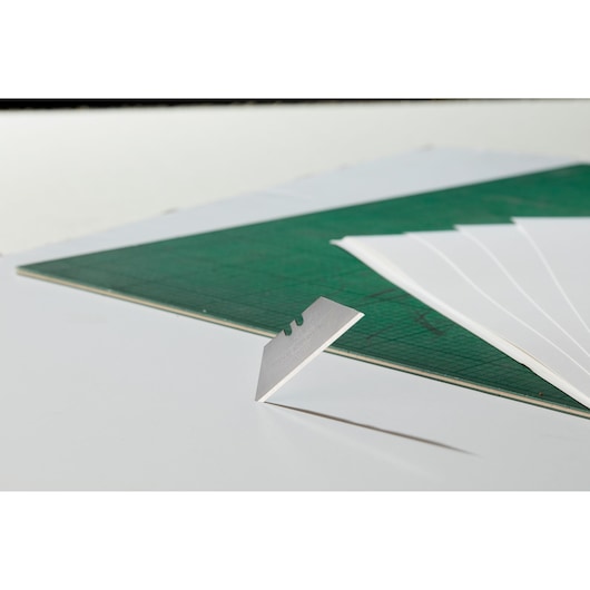 STANLEY 0-11-921 razor blade on white surface with green cutting mat and white sheets, angled view.