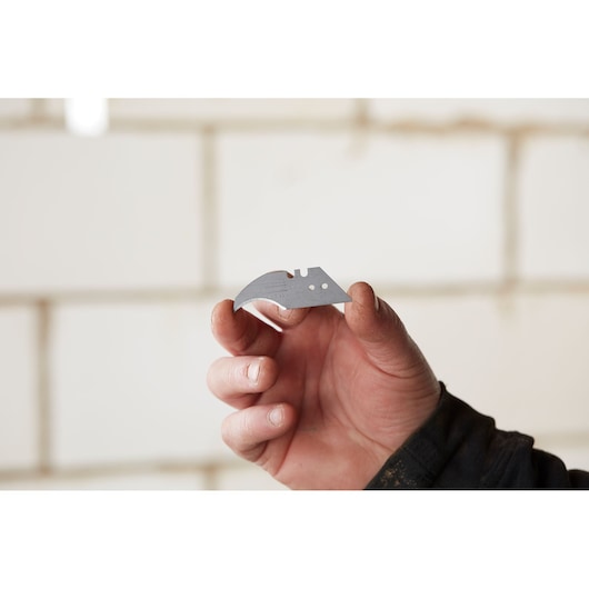Photo of STANLEY 0-11-952 utility knife blade held in hand, showing sharp edge and mounting holes.