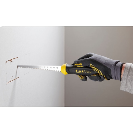 STANLEY 0-20-556 hand saw with black and yellow FatMax handle cutting drywall, close-up photography.