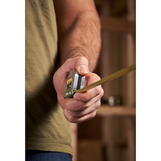 STANLEY 0-32-109 tape measure held in hand, yellow retractable blade extended, close-up photography.