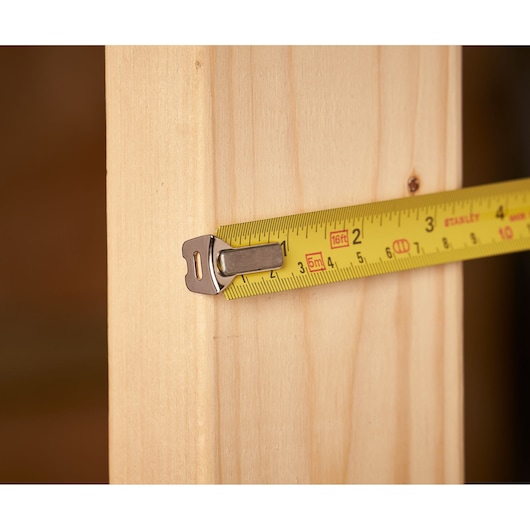 STANLEY 0-33-158 tape measure close-up on wood, yellow blade with black markings, photography product.