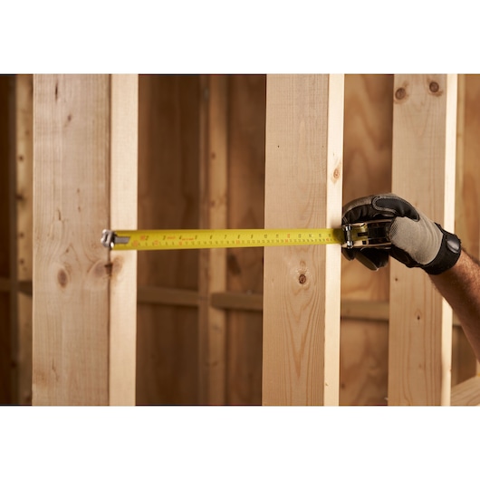 STANLEY 0-33-158 tape measure photo measuring wooden studs in construction framing.