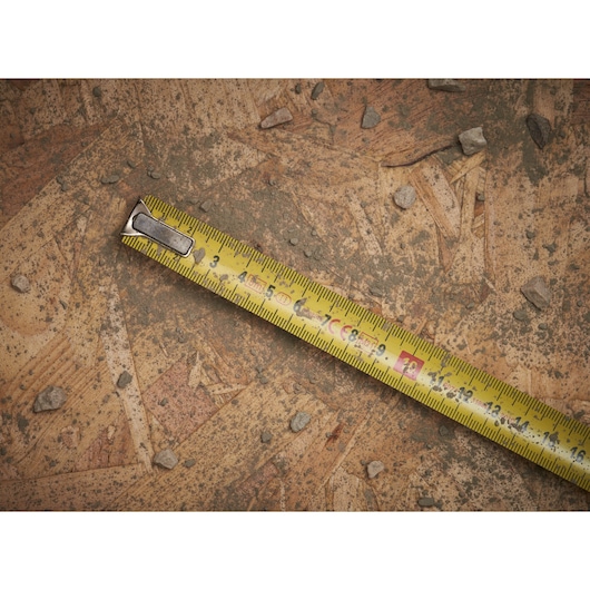STANLEY 0-33-191 yellow tape measure on dusty wooden surface with scattered small stones.