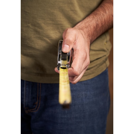 STANLEY 0-33-191 tape measure held in hand, yellow measuring blade extended, photography close-up.