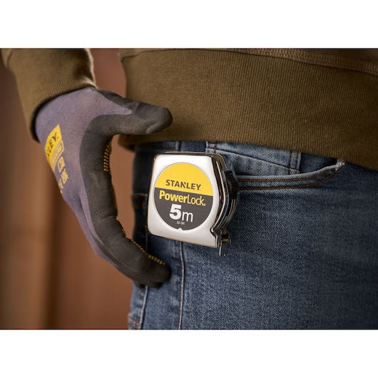 STANLEY 0-33-191 PowerLock 5m tape measure clipped to jeans pocket, close-up photo.