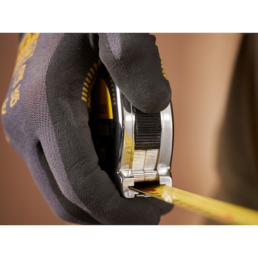 STANLEY 0-33-191 tape measure held in gloved hand, photography showing side view and yellow measuring blade.