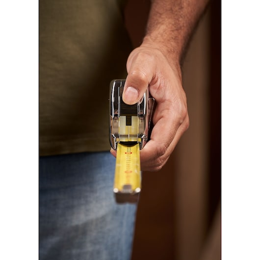 STANLEY 0-33-195 tape measure held in hand, yellow measurement blade extended, close-up angle.