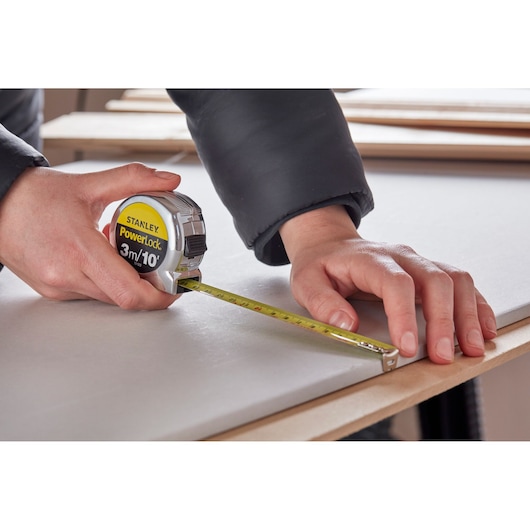 Photo of STANLEY 0-33-523 tape measure in use on a work surface, measuring wood, close-up angle.