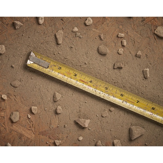 STANLEY 0-33-526 measuring tape with yellow blade on dusty, rocky ground, product photography.
