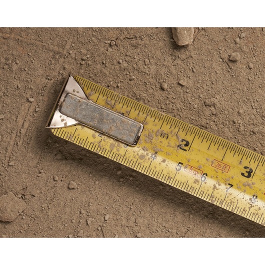 STANLEY 0-33-526 yellow tape measure with metal clip, close-up on dirt, numbers and markings visible.