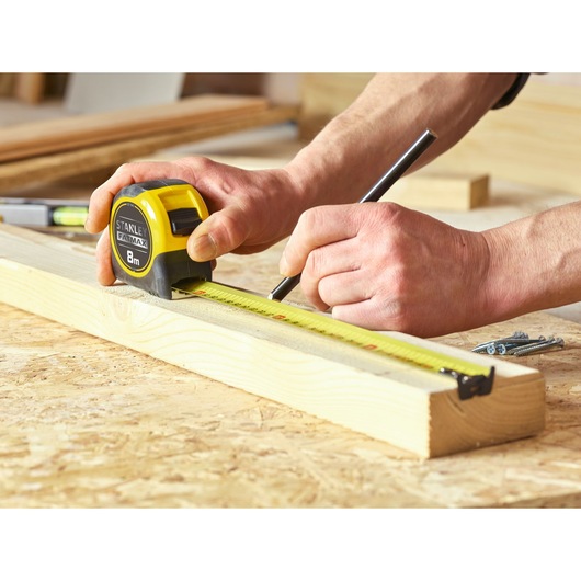 Stanley 0-33-728 tape measure in use on wood, yellow and black, photography of marking measurements.