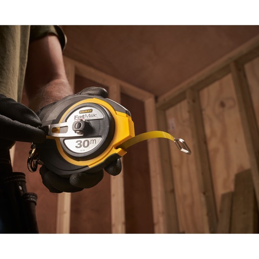 STANLEY 0-34-134 FatMax 30m tape measure held in gloved hand at a construction site.
