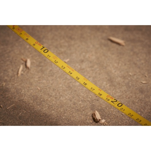 STANLEY 0-34-134 yellow measuring tape photography, close-up on sandy surface.