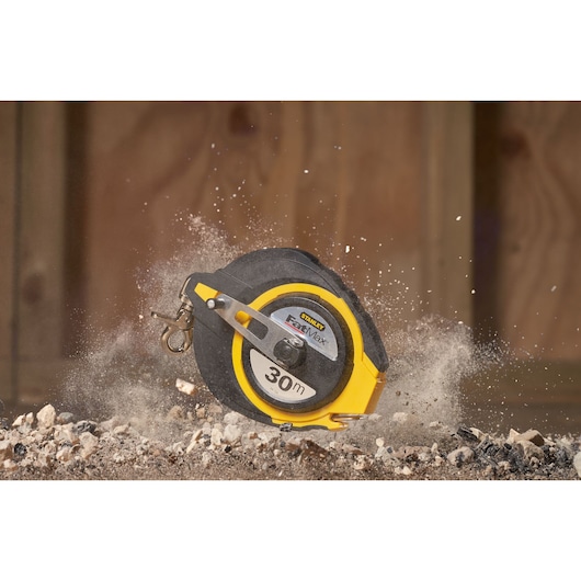 STANLEY 0-34-134 tape measure, 30m, black and yellow case, photographed on construction debris.