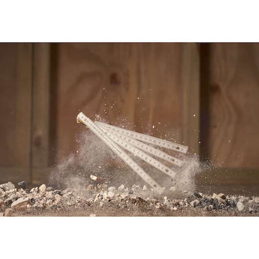 STANLEY 0-35-305 foldable ruler photography, white ruler in mid-action above rubble and dust.