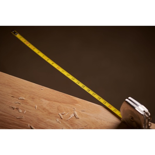 STANLEY 0-39-055 tape measure extended on wood surface with wood shavings, side angle photography.