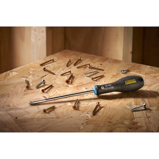 STANLEY 0-65-337 screwdriver with black handle on wooden surface, surrounded by various screws.