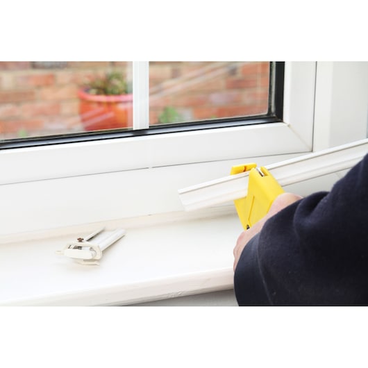 STANLEY 0-70-450 mitre box set on a window sill with white trim being cut, close-up photography.