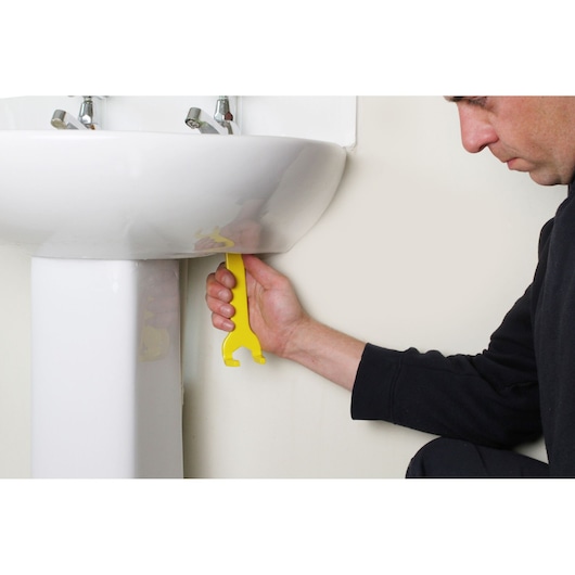 STANLEY 0-70-454 yellow plastic basin wrench in use for tightening under sink.
