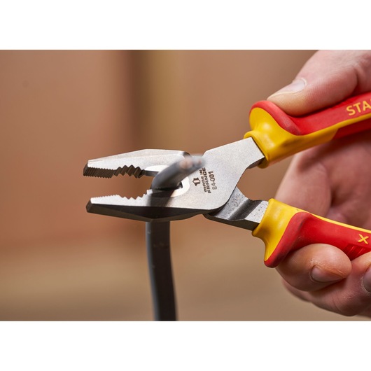 STANLEY 0-84-001 pliers with red and yellow handles cutting wire, close-up photography.