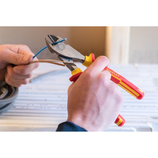 Stanley 0-84-004 insulated diagonal cutting pliers used to cut electrical wires, close-up in hand.