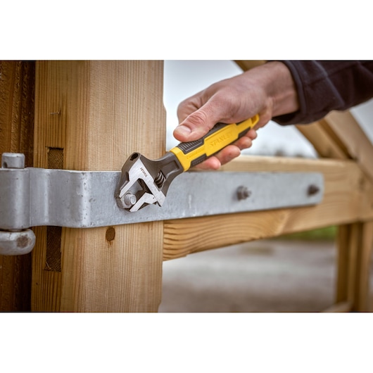 STANLEY 0-90-948 adjustable wrench used on a gate bolt, close-up outdoor photography.