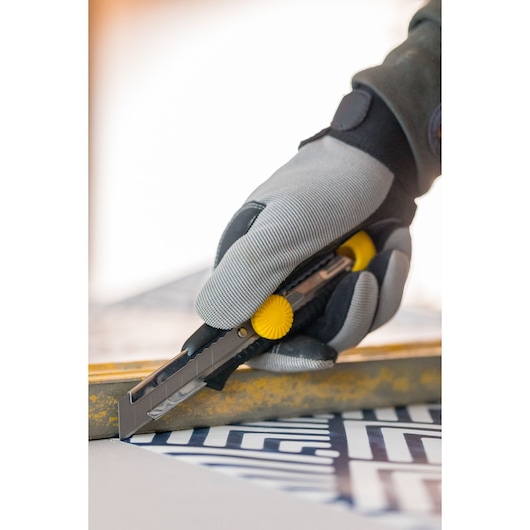 STANLEY 1-10-418 utility knife with yellow wheel, used by gloved hand to cut material.