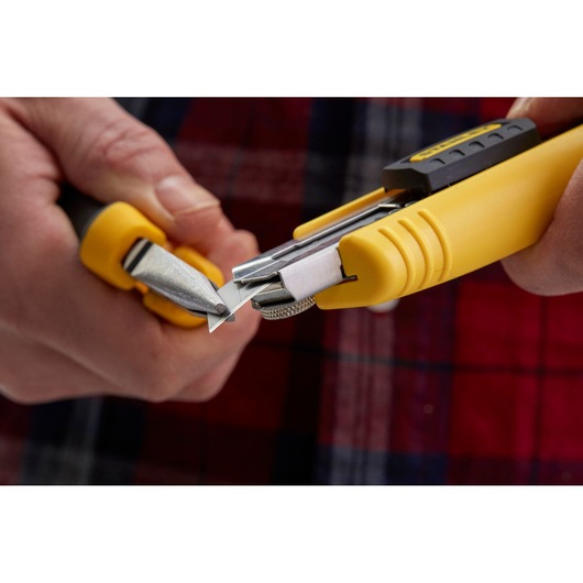 Close-up of STANLEY 1-10-481 yellow utility knife, person snapping off blade segment.