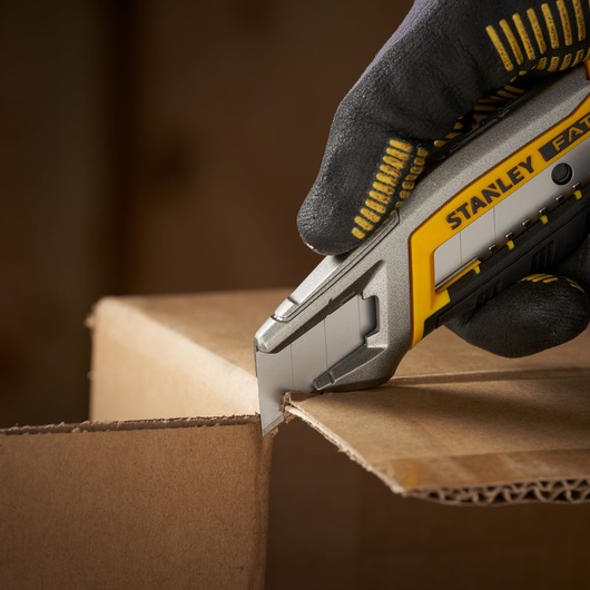 Stanley 1-11-301 utility knife cutting cardboard, close-up, photography of product in use.