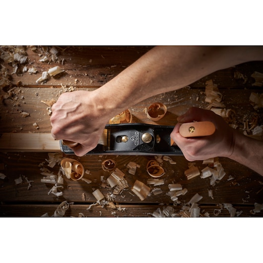 Photo of STANLEY 1-12-137 hand plane in use on wood, wood shavings on a workbench.