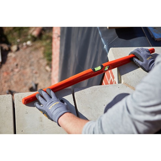 STANLEY 1-42-315 spirit level used on masonry by gloved hands, product photography, angled view.
