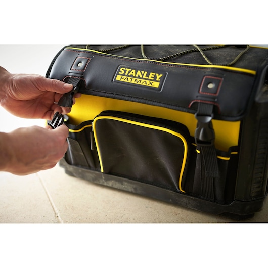 STANLEY 1-79-213 tool bag, black and yellow, front angle, hands fastening side buckle.