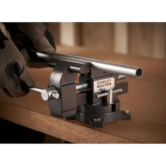 STANLEY 1-83-065 workshop vise clamping metal pipe on wooden bench, close-up side angle.
