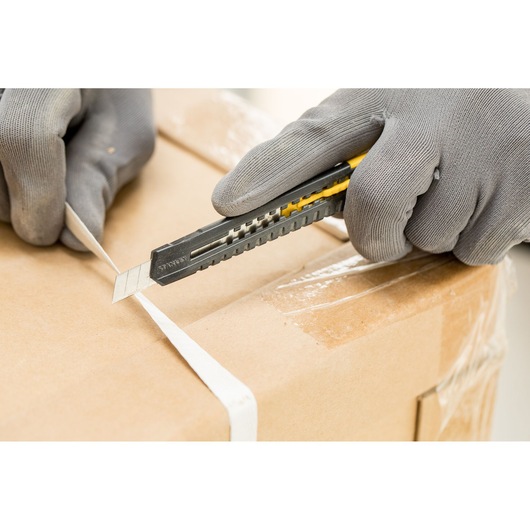 STANLEY 2-10-150 utility knife cutting box strap, close-up photo with gloved hands, product photography.