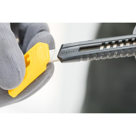 Photo of STANLEY 2-10-150 utility knife with black handle and yellow blade snapper, close-up in use.