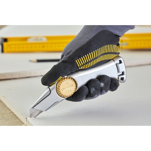 STANLEY 2-10-550 utility knife in gloved hand cutting drywall, close-up action shot, tool photography.