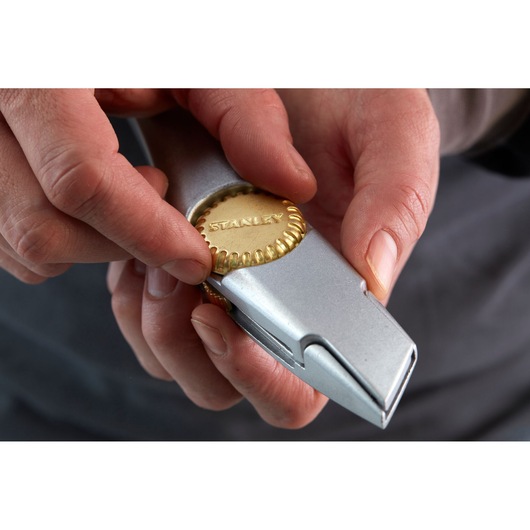 STANLEY 2-10-550 utility knife close-up, showing hands adjusting brass wheel lock.