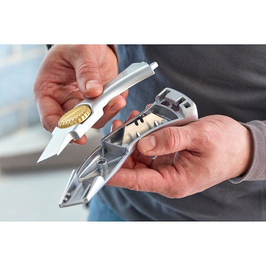 Photo of STANLEY 2-10-550 utility knife being opened to show internal blades in a hand.