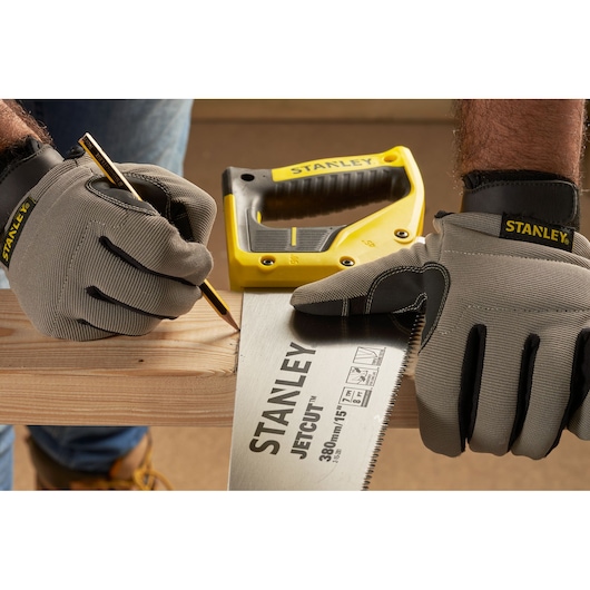 Photo of STANLEY 2-15-281 hand saw on wood, worker with STANLEY gloves marking cut line, photography category.