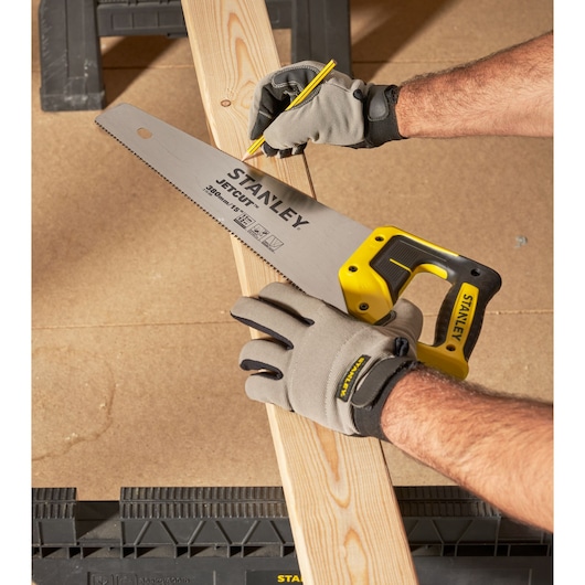 STANLEY 2-15-594 hand saw with yellow handle held on wood plank, close-up angle.