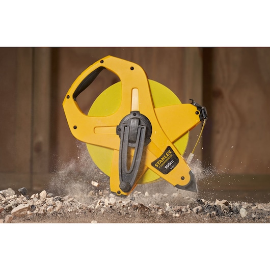 STANLEY 2-34-777 yellow open reel measuring tape on construction site, close-up view.
