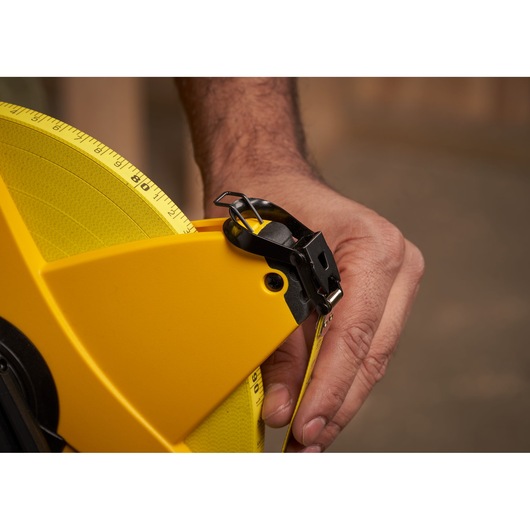 Photo of STANLEY 2-34-777 yellow open reel measuring tape held by hand, close-up view.