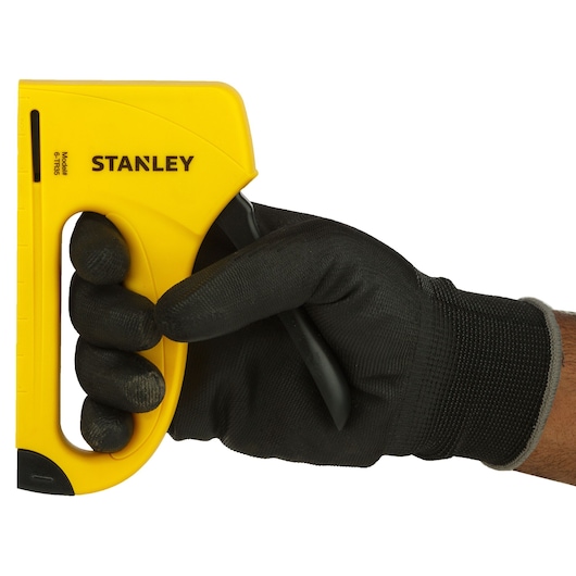 Photo of STANLEY 6-TR35 yellow hand stapler held in a gloved hand, left-side angle, product category: Photography.