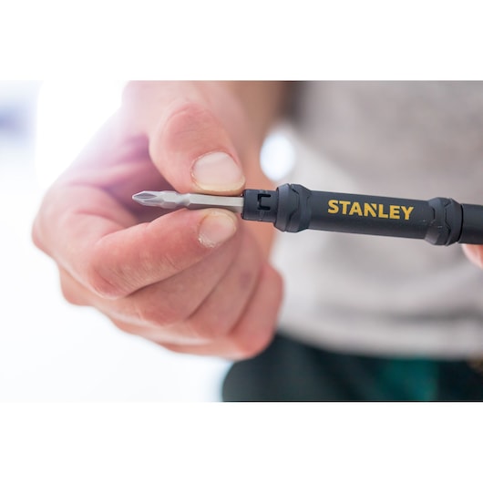 Photo of STANLEY 66-344M screwdriver with black handle and yellow logo held in hand, close-up view.