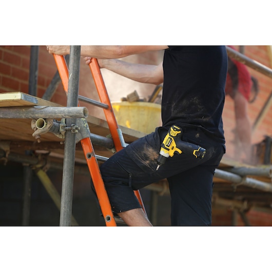 STANLEY FMC010LB cordless drill in holster on worker's hip, construction site background.