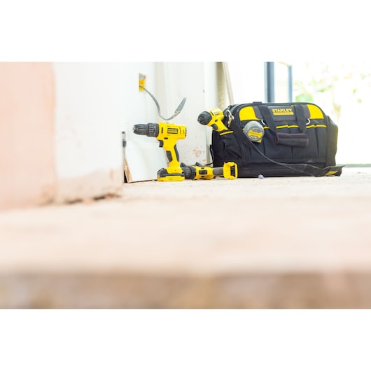 STANLEY FMC041S2 cordless drill set with yellow tools and black tool bag on floor, side angle.